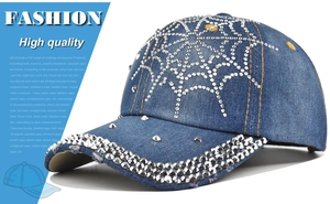 Detail showing blue denim baseball cap with rhinestone spider web pattern and metal studs