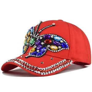 Macro detail of red baseball cap with colorful rhinestone butterfly and studded brim