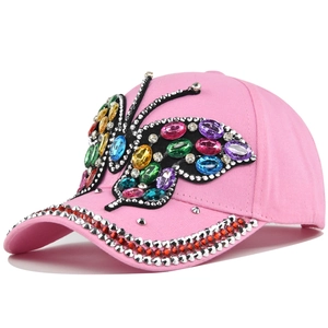 Close-up of pink baseball cap featuring a colorful rhinestone butterfly and studded brim