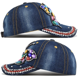 Macro shot of blue denim baseball cap featuring colorful gemstone butterfly and rhinestones