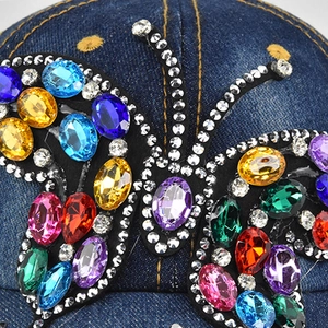 Close-up of colorful gemstone butterfly motif on blue denim baseball cap details
