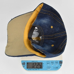 Detail shot of the denim baseball cap showing its weight of 122.5g on a scale