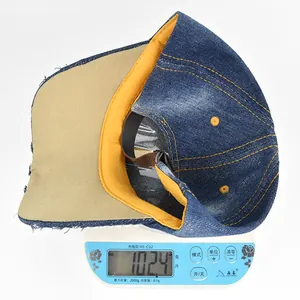 Detail view of denim cross baseball cap weighing 102.4 grams on a digital scale