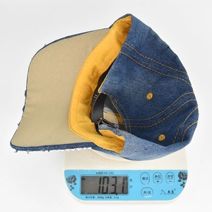 Weight measurement of the cross denim baseball cap on a digital scale showing 103.1 grams