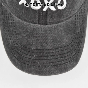 Detail of white 3D XOXO embroidery and precision stitching on dark grey washed cotton cap
