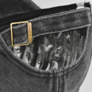 Detail of adjustable bronze metal buckle and washed denim texture on baseball cap