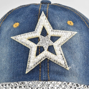 Détail du motif étoile en perles et strass sur la casquette de baseball en jean bleu