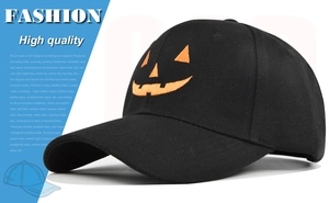 Detailed close-up of orange Halloween pumpkin embroidery on black cotton baseball cap