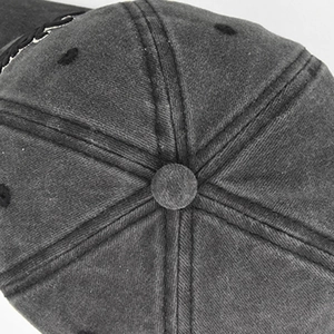 Macro view of the six-panel crown and top button on a washed grey cotton baseball cap