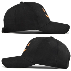 Detail of black baseball cap with orange Halloween pumpkin embroidery and cotton texture