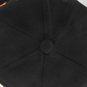 Detailed macro view of the top button and six-panel stitching on this black cotton baseball cap