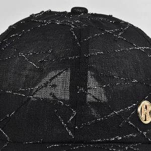 Macro shot of black mesh baseball cap featuring silver glitter stitching and a metal R logo