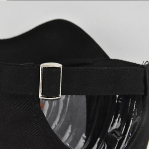 Close-up of the adjustable metal buckle and cotton twill fabric on the black baseball cap