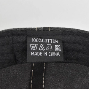 Detailed close-up of the 100% cotton material label and care symbols on the baseball cap