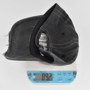 Detail shot of vintage dark grey washed baseball cap showing weight on digital scale