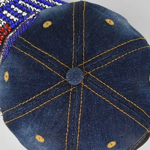 Close-up of denim baseball cap featuring yellow stitching and sparkling rhinestone details