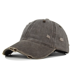 Detailed view of the distressed edges and frayed holes on a charcoal grey baseball cap