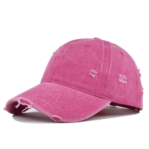 Detail view of distressed rose red washed cotton baseball cap with ripped fabric texture