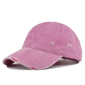 Close-up of pink washed cotton baseball cap with vintage distressed holes and frayed brim