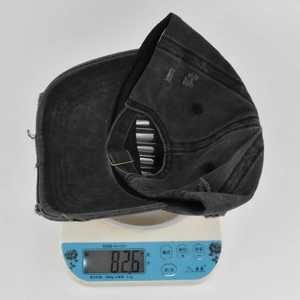 Detail shot of distressed black baseball cap on digital scale weighing 82.6 grams