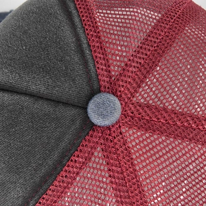 Macro detail of breathable red mesh fabric and grey twill cotton on top of the trucker hat