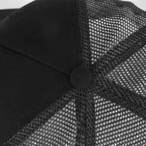 Detailed close-up of breathable black mesh fabric and top button on a sports trucker hat