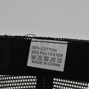 Detail view of cotton blend material label with care instructions on a black mesh cap