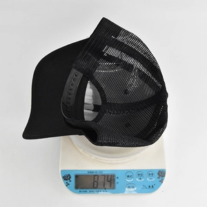 Detailed view of a black trucker hat on an electronic scale showing a weight of 87.4g