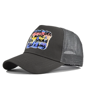 Détail d'une casquette trucker grise avec impression d'art et texte brodé de film