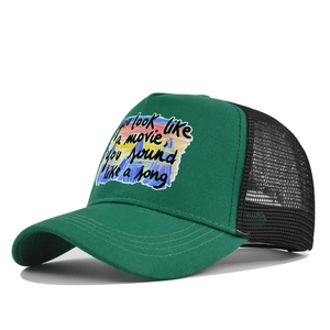 Détail de la casquette trucker vert et noir avec des paroles imprimées sur le panneau avant