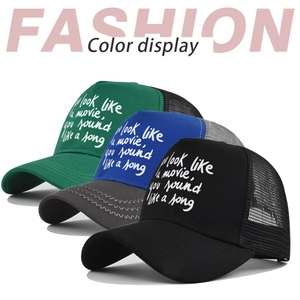 Close-up of mesh baseball caps in green, blue, and black with screen-printed quote
