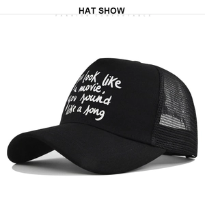 Side view of black mesh trucker hat with white script movie quote text on white background