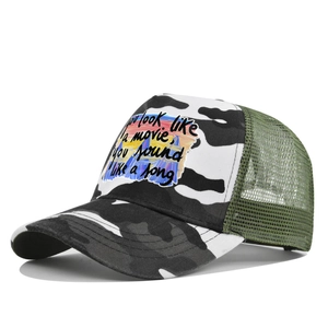 Détail de casquette trucker imprimé vache avec écusson coucher de soleil et filet vert