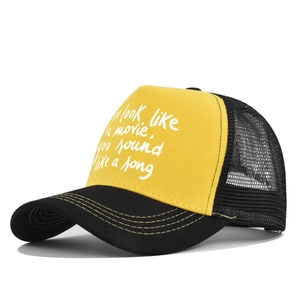 Detail view of the yellow trucker hat with white movie quote print and black mesh