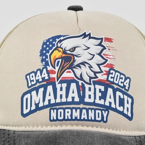 Close-up detail of eagle print and Omaha Beach Normandy text on distressed baseball cap