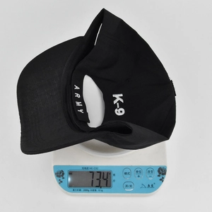 Detailed top view of a black tactical K-9 baseball cap on a digital scale weighing 73.4g