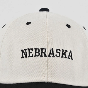 Detail der Nebraska-Stickerei auf einer beigen Baseballkappe mit schwarzen Luftlöchern