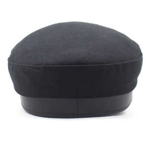 Detail of black wool newsboy cap featuring a matte PU leather brim and metal side button