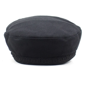 Detailed close-up of a vintage black wool baker boy hat featuring braided rope trim details
