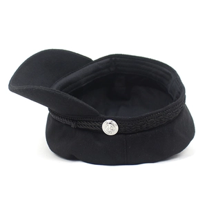 Detailed view of the black wool baker boy hat with braided rope and anchor button decoration