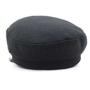 Detail view of black wool newsboy cap featuring leather brim and decorative silver button