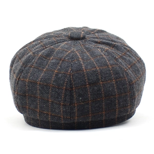 Détail d'une casquette gavroche à carreaux gris avec texture tweed et bouton supérieur
