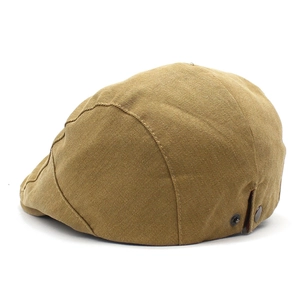 Detailed close-up of the khaki cotton fabric and metal buckle on the side of this beret cap