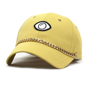 Detail view of yellow baseball cap with eye embroidery and stylish gold metal chain