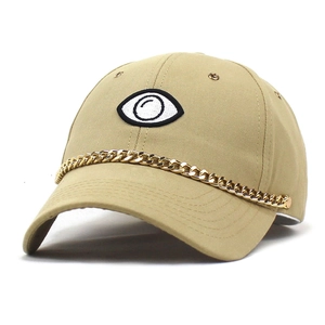 Khaki baseball cap with embroidered eyes and a decorative gold metal chain on the brim