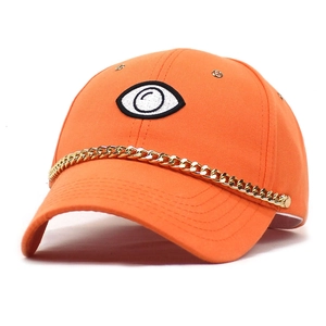 Detail of orange cotton baseball cap featuring large eye embroidery and gold chain link decoration