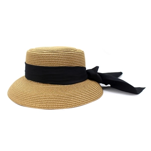 Detail of elegant straw boater hat with a wide black ribbon bow on white background
