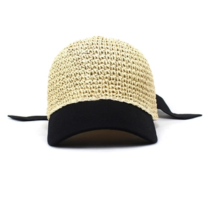 Detail of woven straw baseball cap with hollow mesh design and black bow ribbon