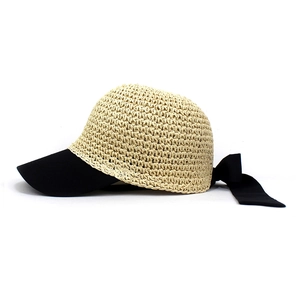 Detail of woven beige straw sun hat with black brim and elegant large rear bow
