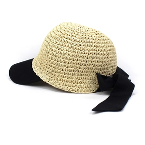 Detail of woven straw sun hat with black contrast brim and large elegant bow